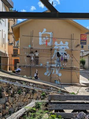 Students from Hongyan No. 2 Middle School painting the Baiya Castle mural from scaffolding