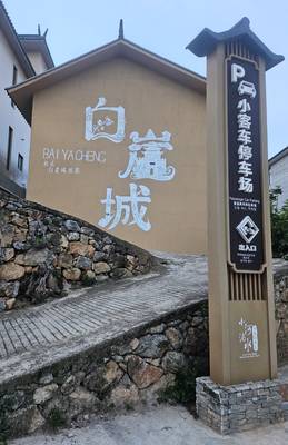 The completed Baiya Castle mural in white calligraphy above a stone retaining wall