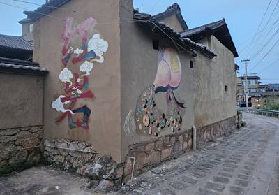 Two finished murals along a village lane at dusk