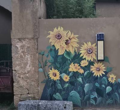 A mural of sunflowers in full bloom on a village wall